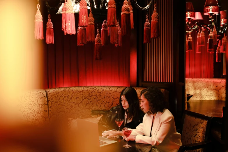 two women sit at the table with wine glasses in hand