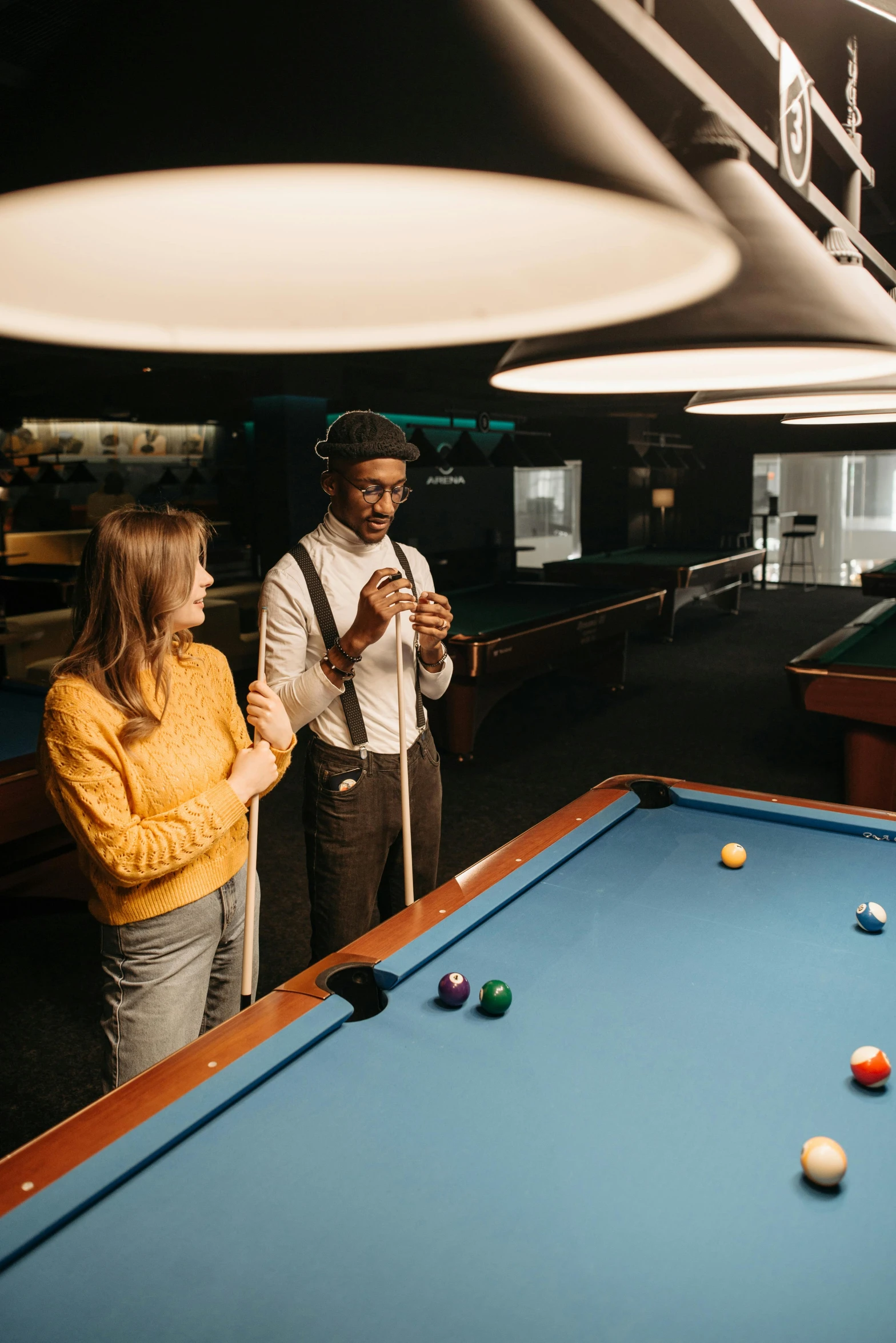 man and woman playing billiards with a bright umbrella