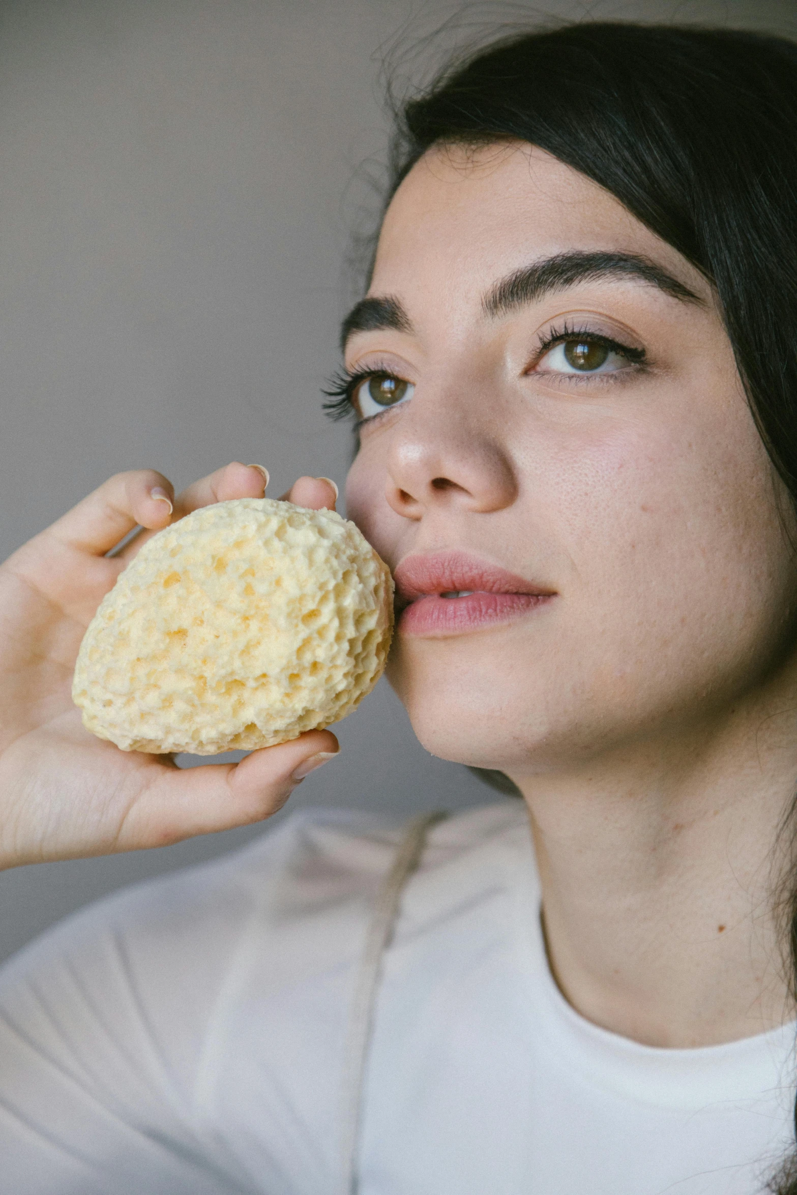 a woman is eating a pastry and staring at the camera