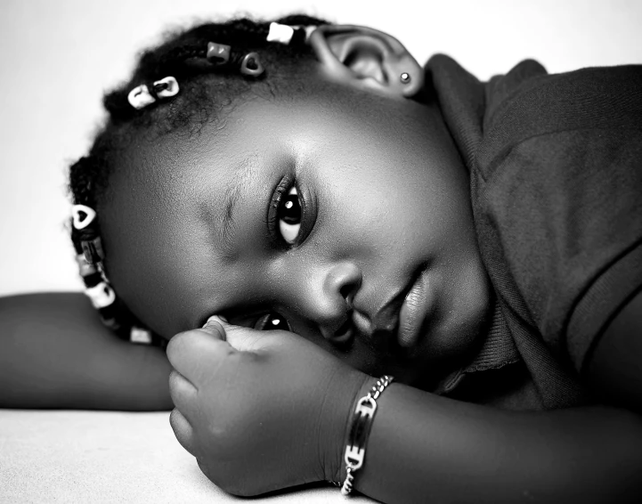 a young black girl wearing jewelry and lying in bed