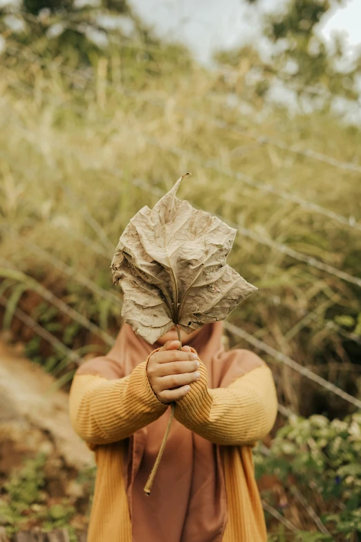 a woman wearing brown holding onto a leaf