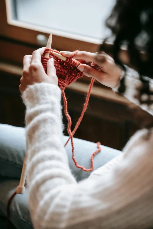 a woman is sitting on a couch knitting