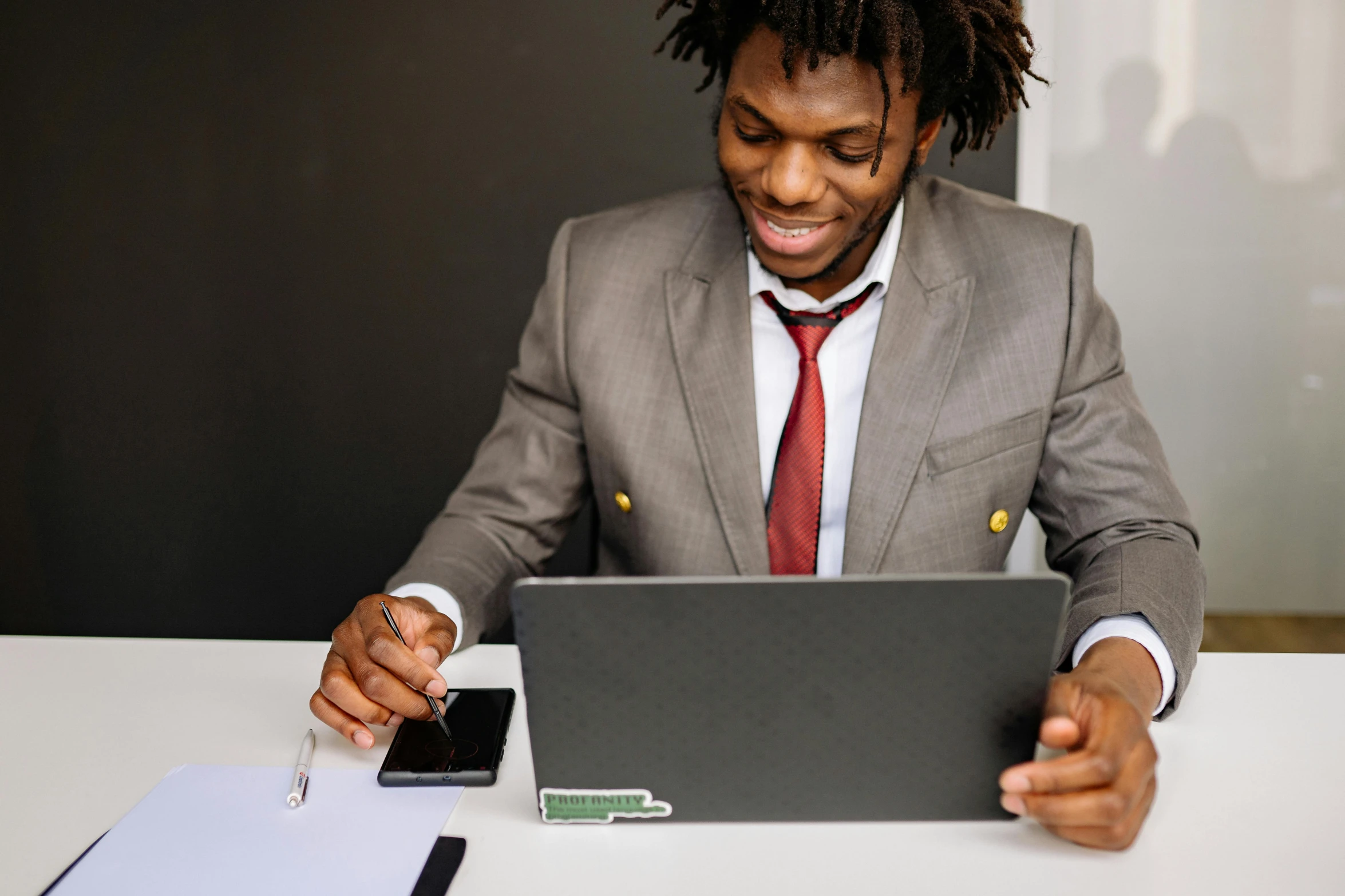 a man wearing a suit sitting at a table looking at a computer screen