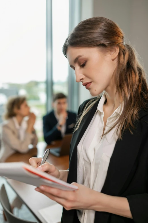 a girl is writing while two other people are working behind her