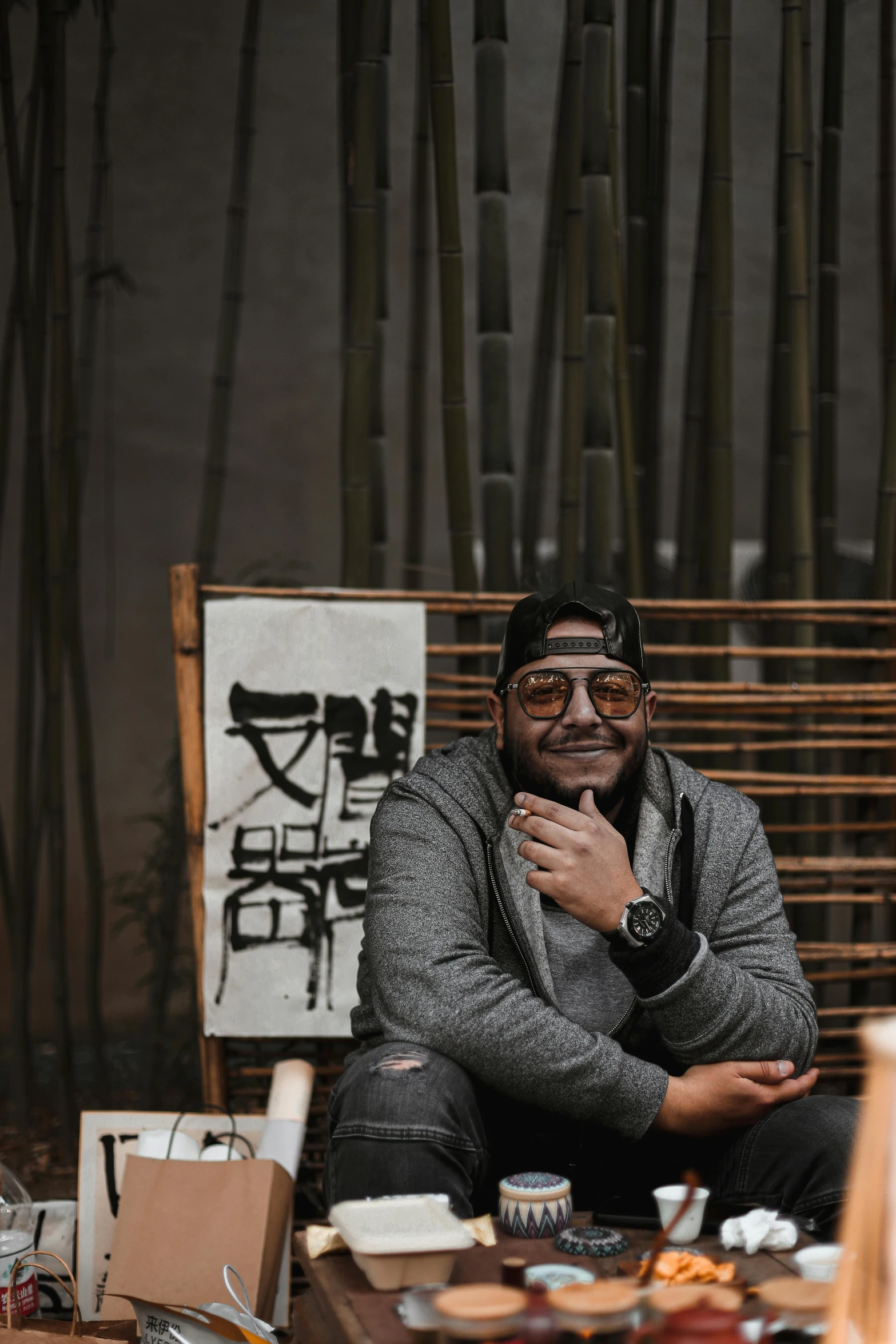 a man sits on a bench in front of some bamboo