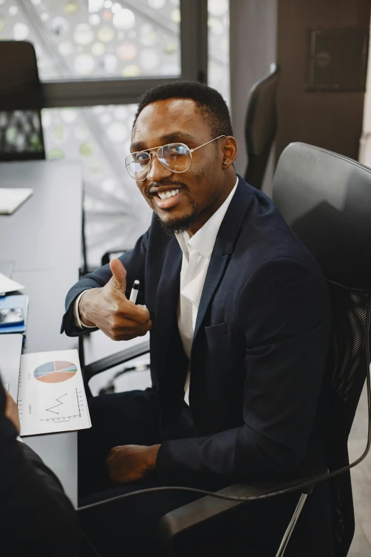 a black man in a suit sitting at a desk