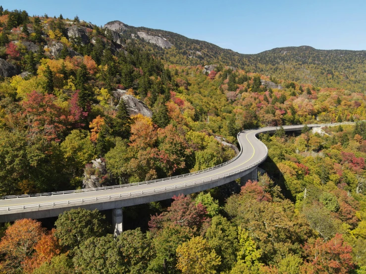 a road goes between two separate hills that have trees and mountains on either side of it