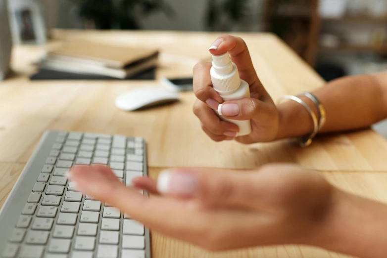 person's hand holding an unopened pill by the keyboard