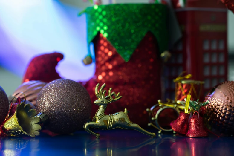 ornaments sit atop a shiny surface with a red and green tinsel covered box