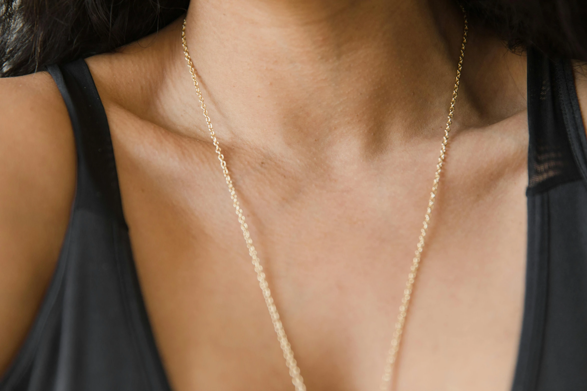 a woman wearing gold necklaces and a black top