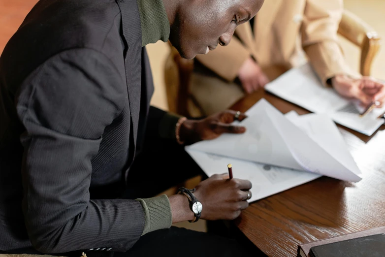 a man who is writing in paper on a desk