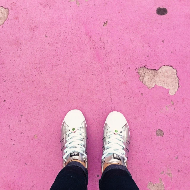 legs wearing tennis shoes standing on pink ground