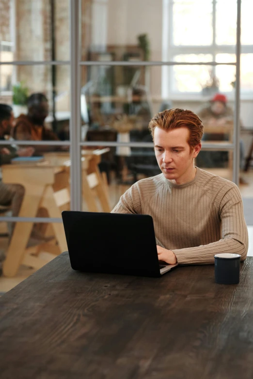 the man looks at his laptop while sitting at a table