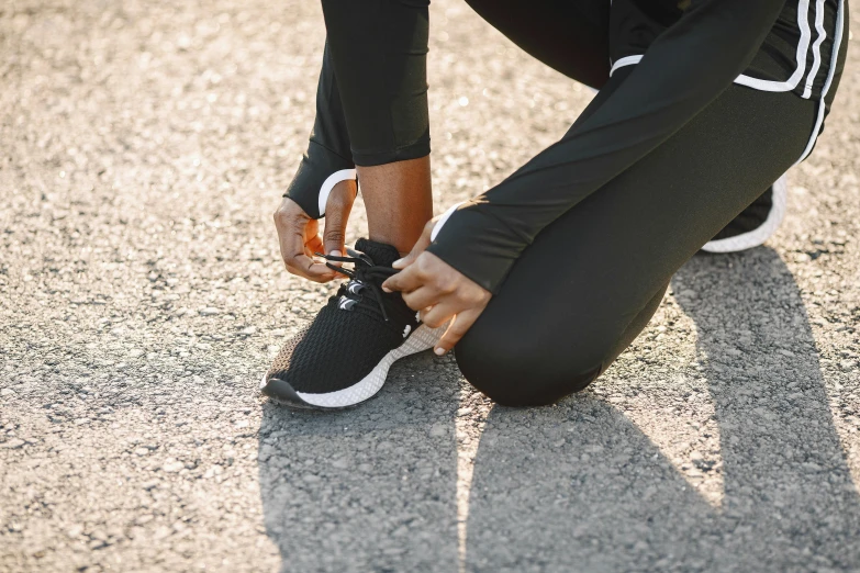 a young woman tying her tennis shoe with black laces