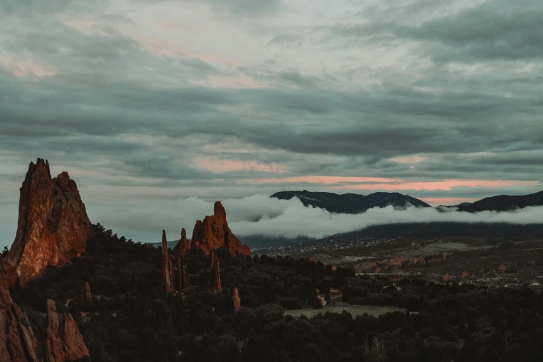 a mountain range with clouds above it in the sunset