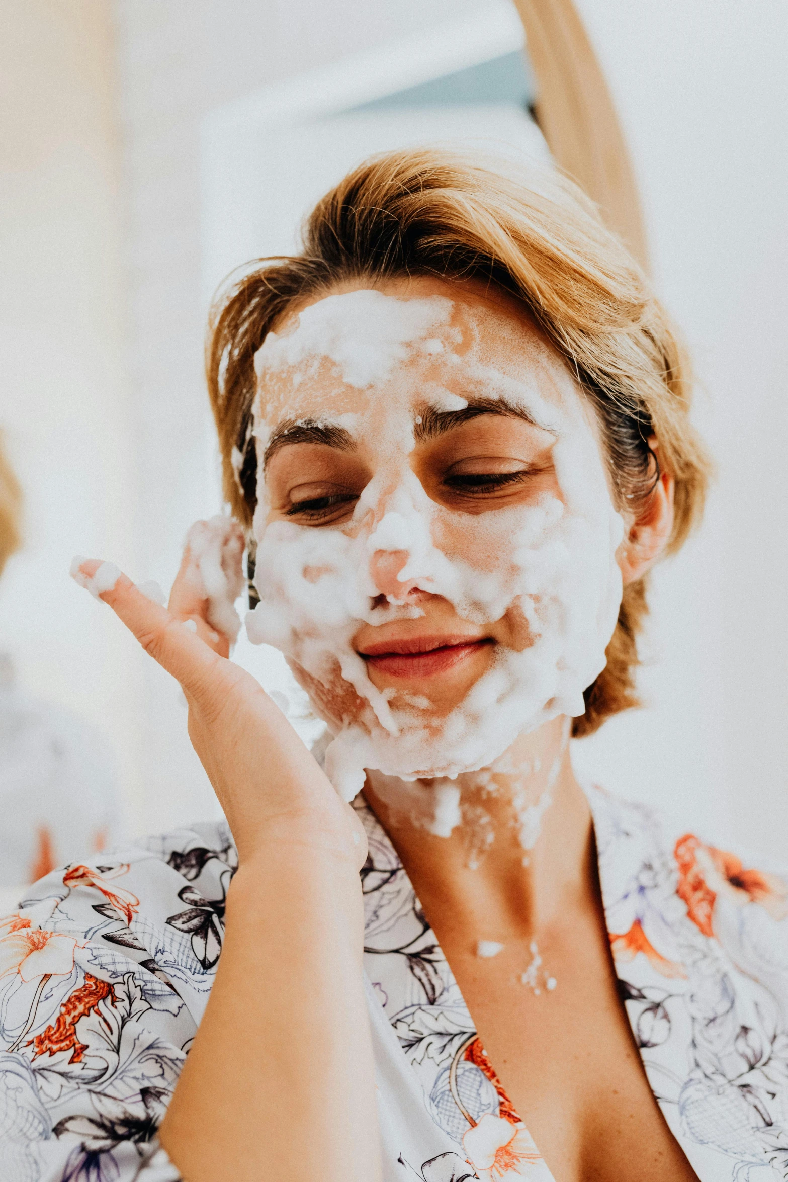 woman covered in foam and facial mask in bathroom