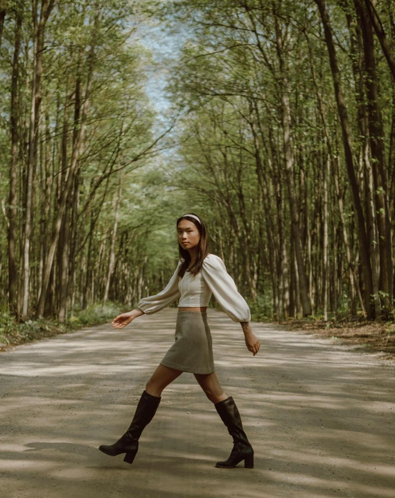 a woman is walking down the road and there are trees lining the road