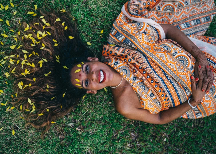 a woman laying down on the grass posing for a pograph