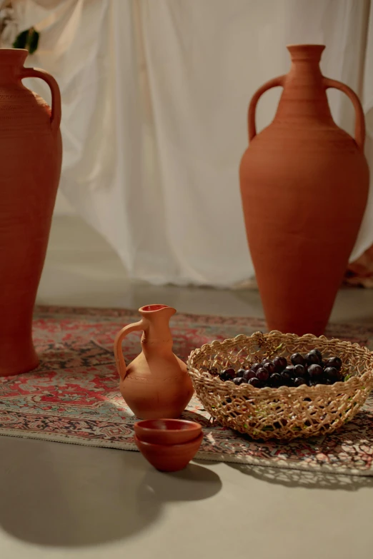 two vases on a rug next to a basket of gs