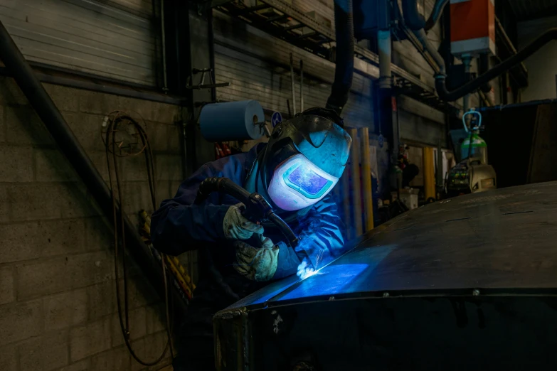 a man wearing a blue safety suit and face mask operating a tool