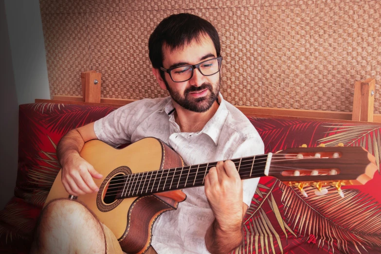 a man is playing an acoustic guitar on a couch