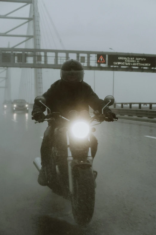 a person on a motor cycle riding across the bridge in fog