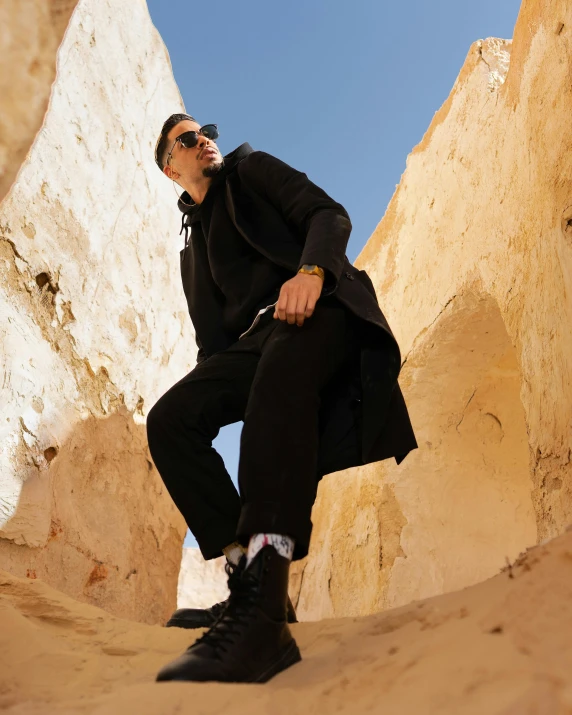 a man wearing black sitting in a desert