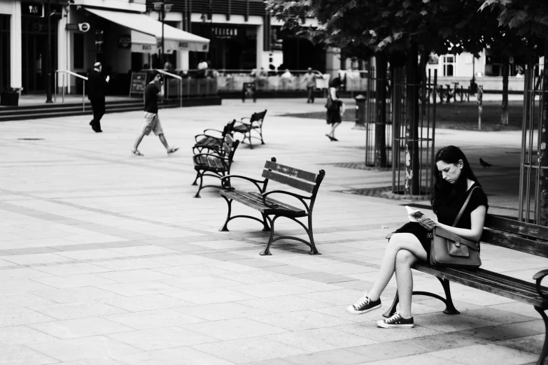 a woman is sitting on a bench reading a book