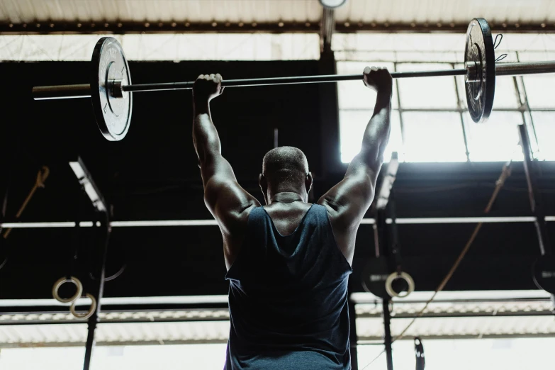 a man holding two barbells over his back