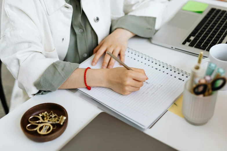 a person in a white coat is writing on a notebook