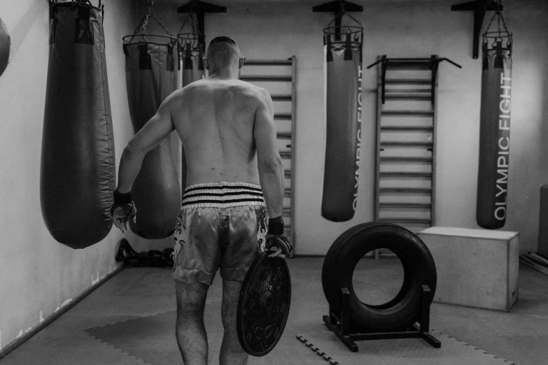 black and white pograph of a young man in his gym with a board