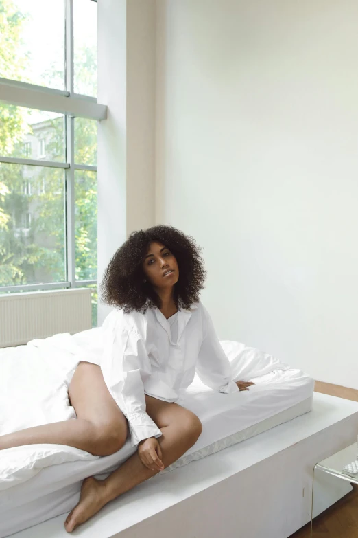 a woman with black hair is sitting on a bed