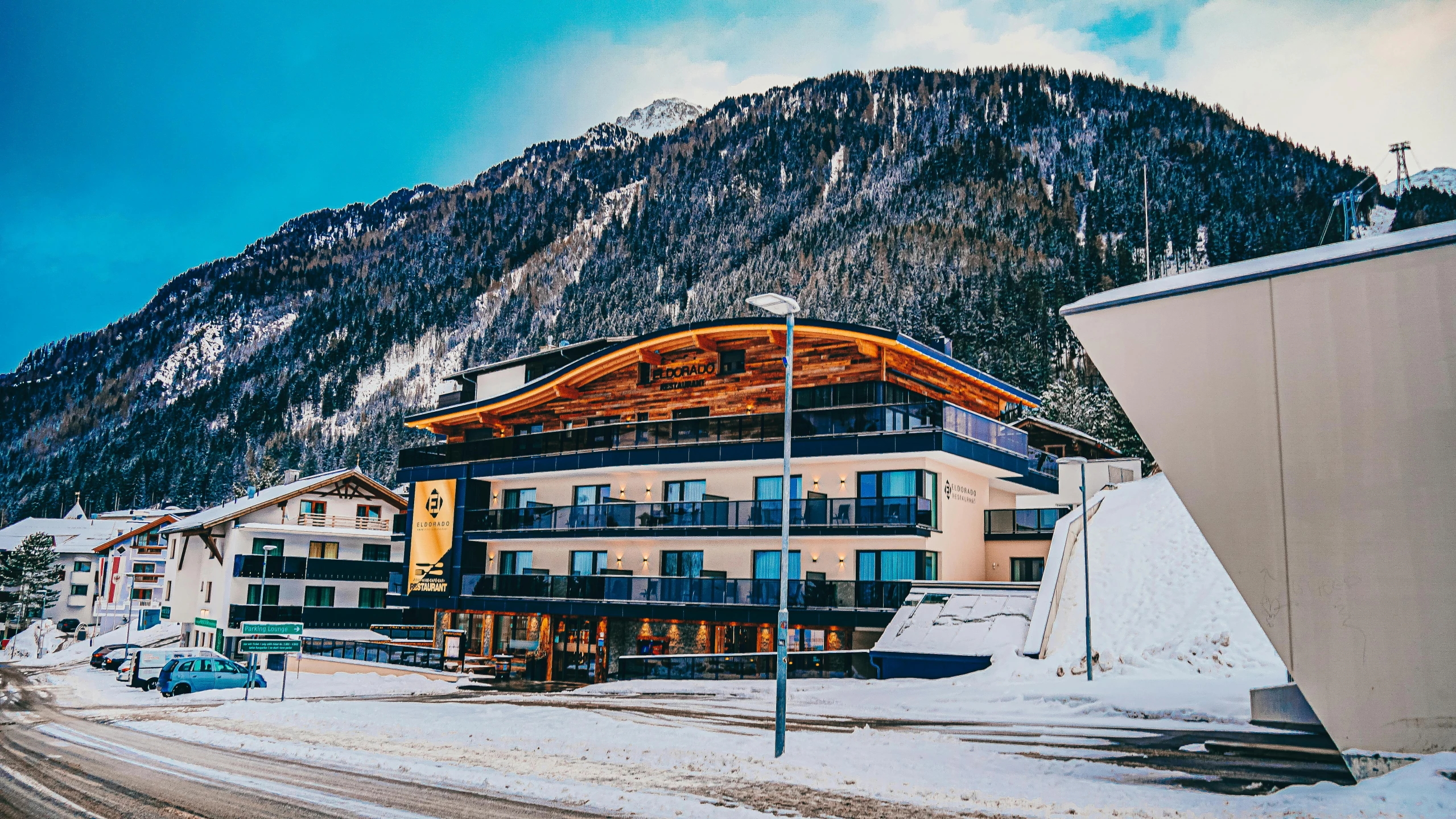 a long road lined with traffic next to a building in the snow