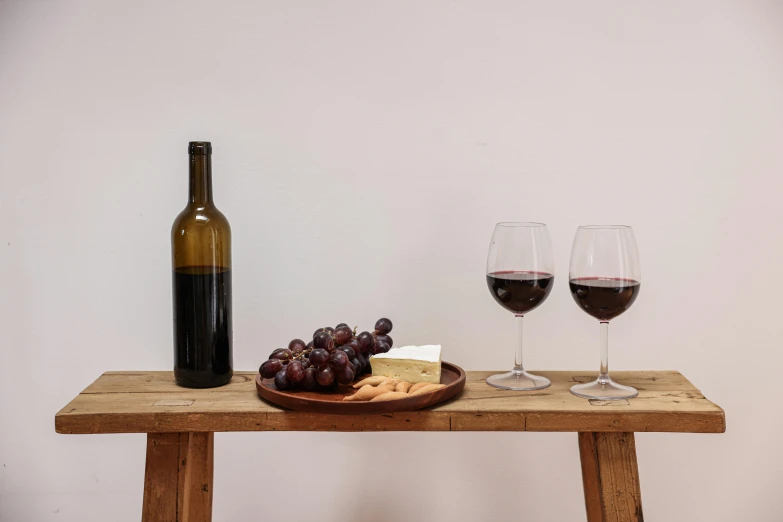 a wine glass on a wood table with food and a bottle