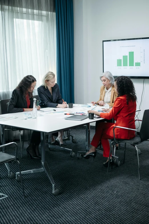 three women sitting at a conference table having a meeting