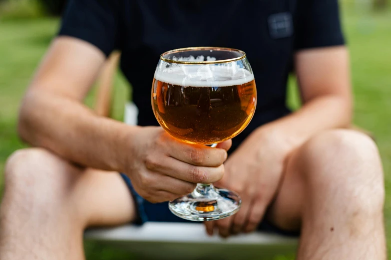 someone sitting down holding a glass with some beer