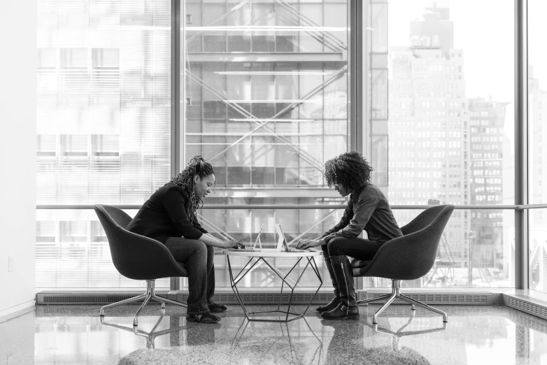 two people sitting at a table in a large office