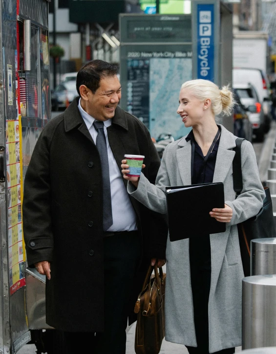 an older couple walking down the street holding coffee