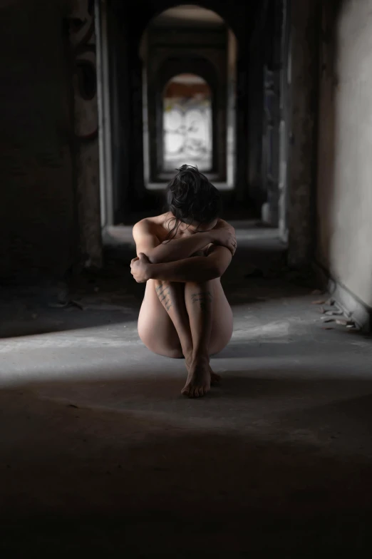 a  woman sitting on the floor in an abandoned building