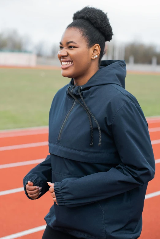 young woman running on the track smiling for the camera