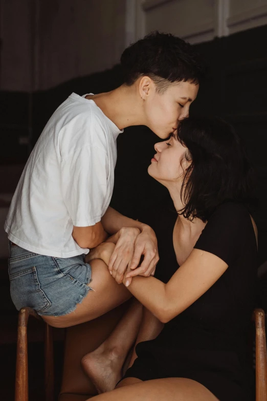 a couple sits on a chair as they both kiss