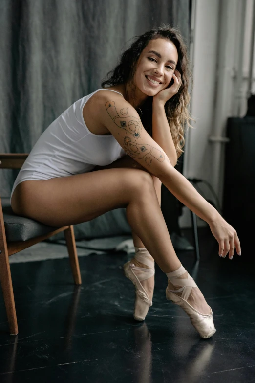 an attractive young woman sits on a chair smiling