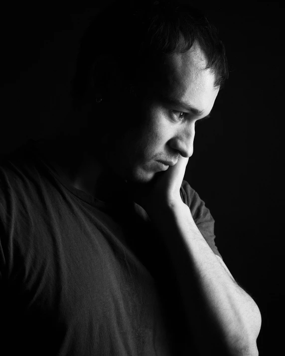 man with his hand to his chin in a dark room