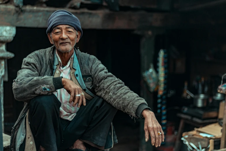 old man sits outside an indian store with no shoes