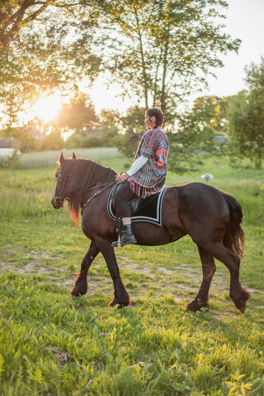 young man riding a horse in the field at sunset