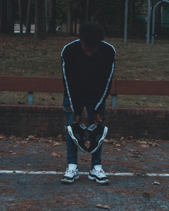 a man stands in a parking lot holding a skateboard