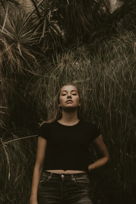 a girl is in black shirt and jeans standing near tree