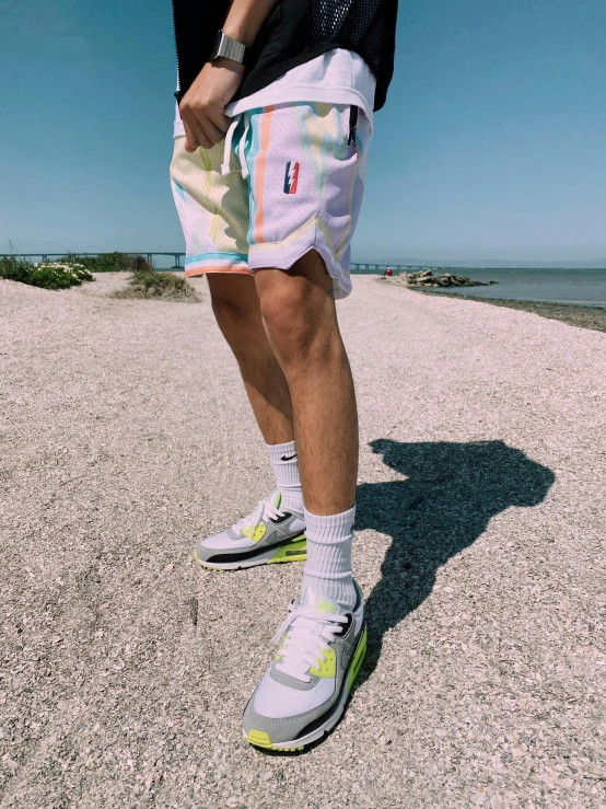 a man wearing adidas shoes and running gear is standing on the beach