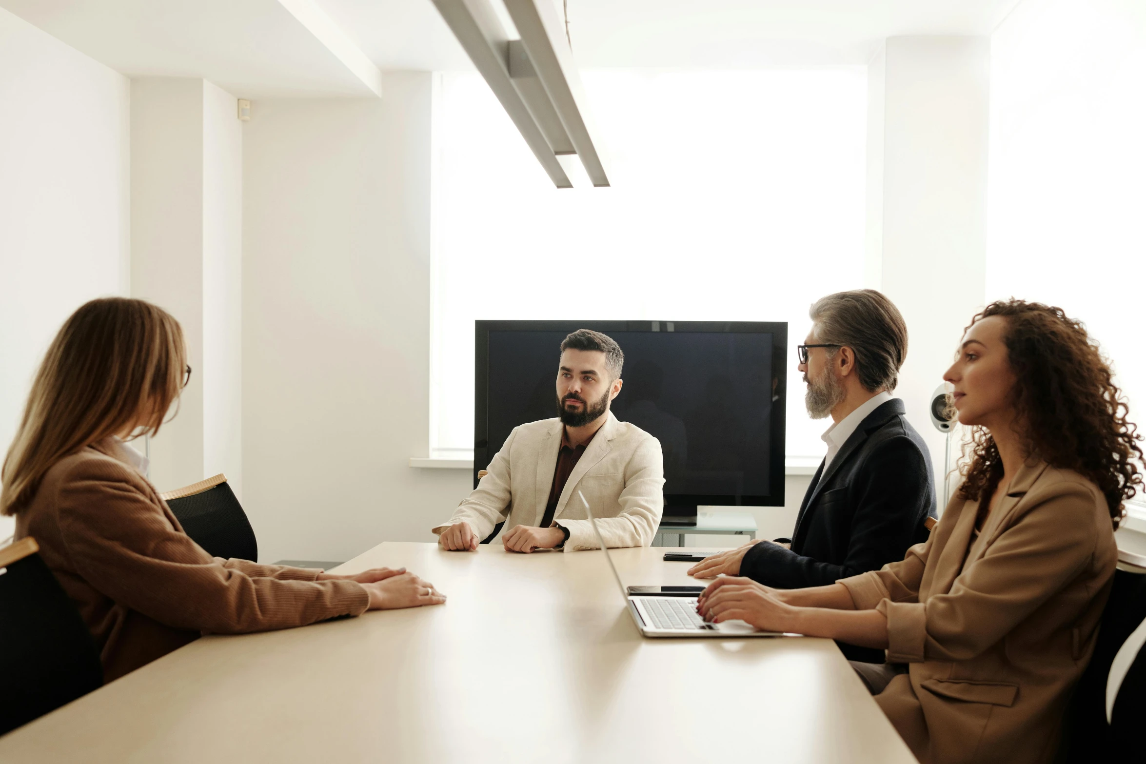 five people in an office meeting in front of a screen