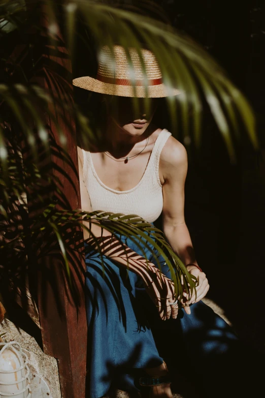 a young woman wearing a straw hat is holding a plant